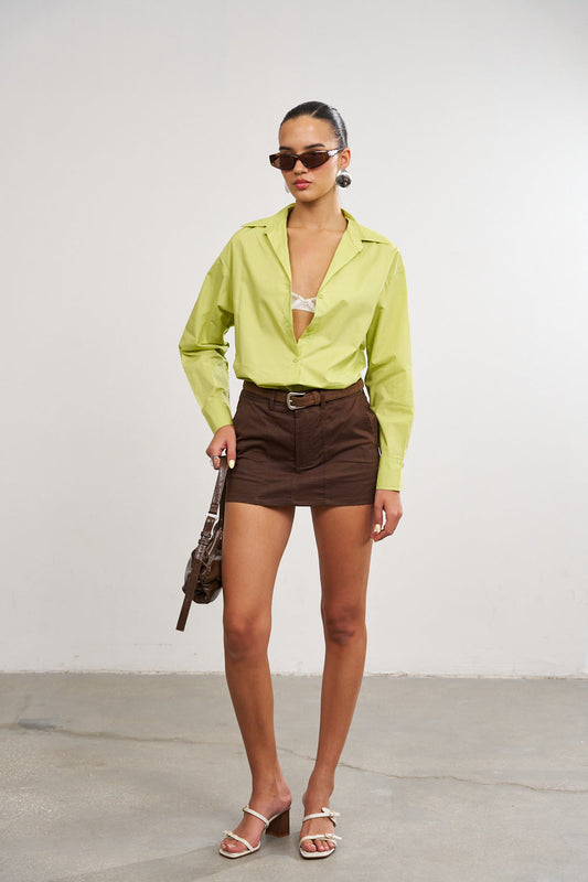 דוגמנית לבושה עם מכופתרת ירוקה וחצאית מיני